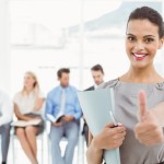 Businesswoman gesturing thumbs up against people waiting for interview