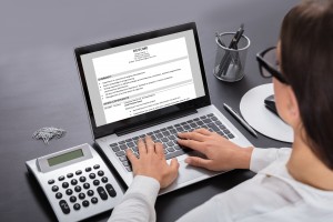 Businesswoman Looking At Resume On Laptop