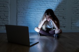 Scared sad girl bullied on line with laptop suffering cyberbullying and harassment feeling desperate and intimidated. Child victim of bullying stalker social media network