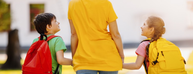 Mother walking with son and daughter on the schoolyard.