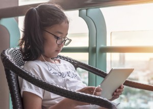 School kid using internet online learning and reading e-book on mobile tablet app for educational studying and playing game for recreational relaxation in digital technology lifestyle