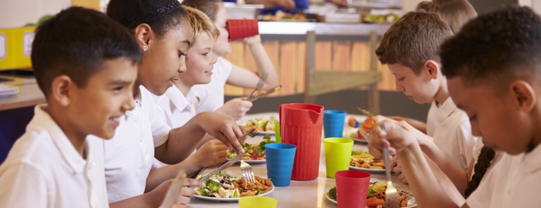 Primary school kids eating at a table in school cafeteria