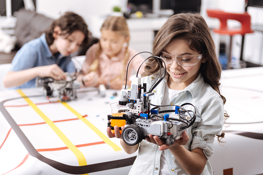 Lovely little girl holding robot at school