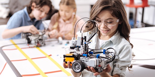 Lovely little girl holding robot at school