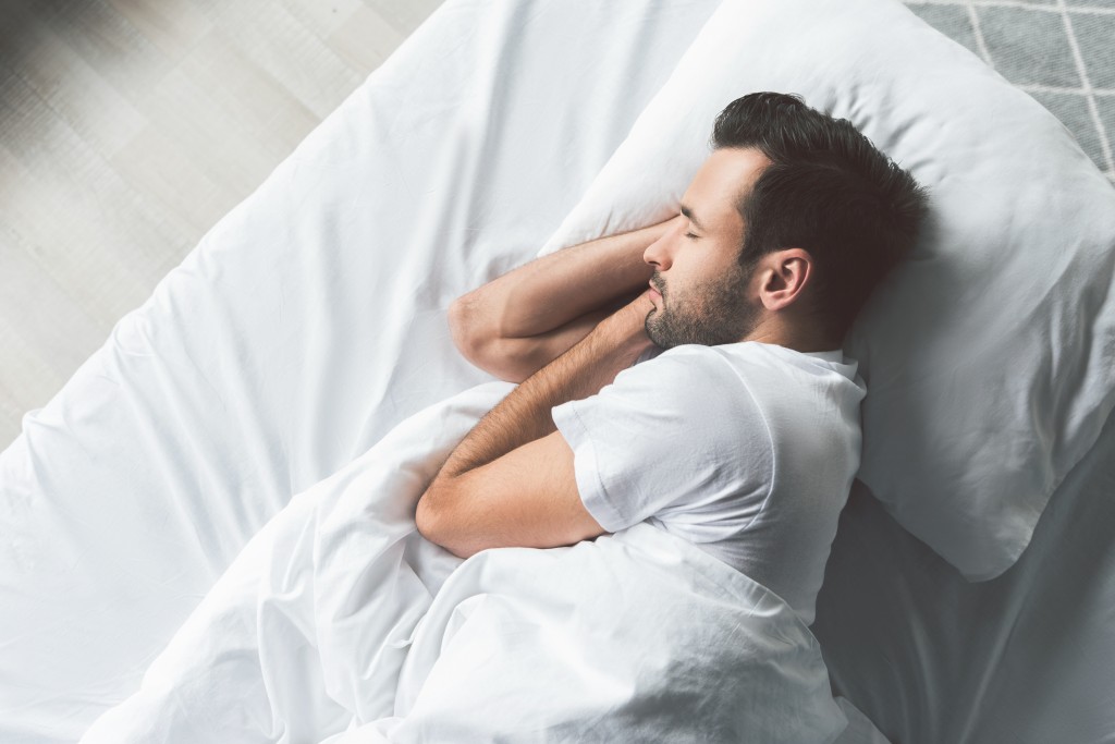 Cute young man sleeping on bed