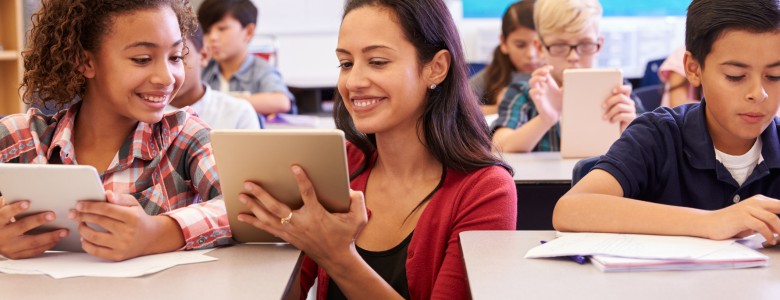 Teacher helping kids with computers in elementary school