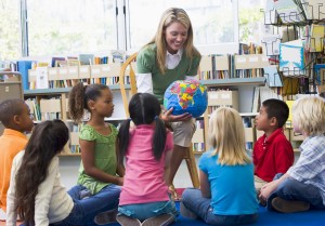 Kindergarten teacher and children looking at globe